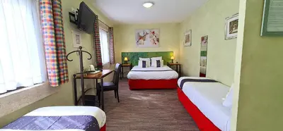 a small room with two beds and a desk at Hotel du Mas in Vinassan