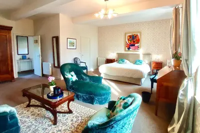 a hotel room with a bed and a couch and chairs at Domaine de Rasigous in Saint-Affrique-les-Montagnes