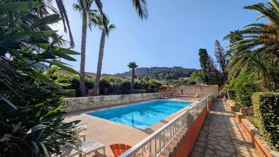a swimming pool in a villa with palm trees at Gite la Capelle près de Sigean Narbonne dans l'Aude à 10 min des plages Méditerranée in Roquefort-des-Corbières