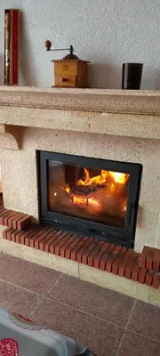a brick fireplace with a fire in it at Maison D architecte chez Huguette in Villalier