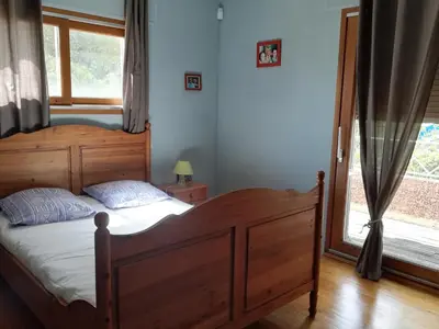 a bedroom with a wooden bed and a window at Maison D architecte chez Huguette in Villalier