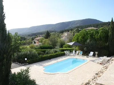 a swimming pool in a garden with mountains in the background at Modern villa in Camplong with private pool in Félines-Minervois