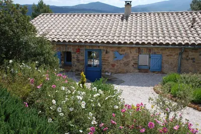 a stone house with a blue door and flowers at Bergerie Marcel in Durban-Corbières