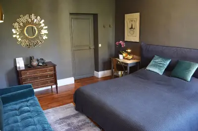 a bedroom with a bed and a couch and a mirror at La Résidence de Gérard in Montréal