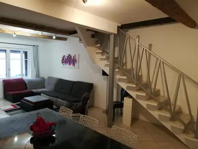a living room with a couch and a staircase at CASA BLANCA à SIGEAN-GÎTE in Sigean