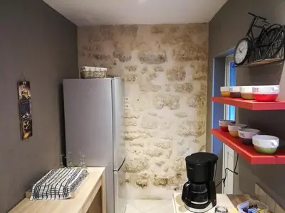 a kitchen with a refrigerator and red shelves at CASA BLANCA à SIGEAN-GÎTE in Sigean