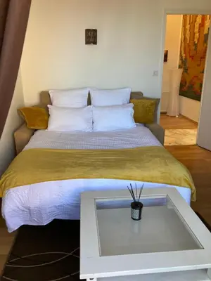 a bedroom with a large bed with a table at Appart Aux deux Colombes avec Balcon et Garage in Pamiers