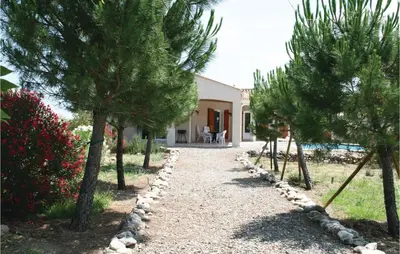 a gravel pathway with trees in front of a house at Stunning Home In Prades Sur Vernazobre in Prades-sur-Vernazobre