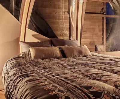 a bed with a wooden headboard and pillows on it at Le Wigwam du Fassac in Saint-Julien-du-Puy