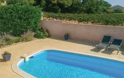 a swimming pool with two chairs next to a wall at Gorgeous Home In Cessenon Sur Orb in Cessenon