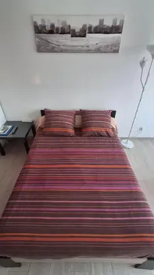 a large bed in a bedroom with a striped blanket at Le Studio des 3 Moulins in Sigean