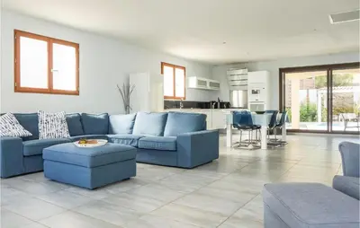 a living room with blue couches and a kitchen at 3 Bedroom Cozy Home In Caunes Minervois in Caunes-Minervois