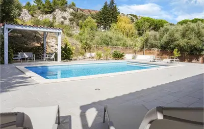 a pool in a backyard with chairs and a patio at 3 Bedroom Cozy Home In Caunes Minervois in Caunes-Minervois