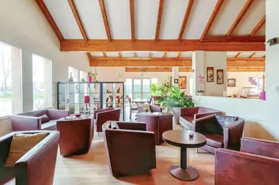 a restaurant with brown chairs and tables and windows at Brit Hotel Confort Castres in Castres