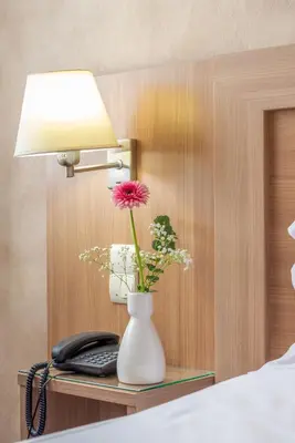 a vase with a flower on a table with a phone at Brit Hotel Confort Castres in Castres