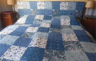 a bed with a blue and white quilt on it at Amazing Home In Prades Sur Vernazobre in Prades-sur-Vernazobre