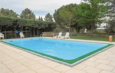 a large swimming pool in a yard with chairs and trees at Lovely Home In Puisserguier With Wifi in Puisserguier