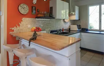 a kitchen with a wooden counter with a clock on the wall at Lovely Home In Puisserguier With Wifi in Puisserguier