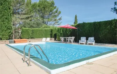 a swimming pool with an umbrella and a table and chairs at Lovely Home In Puisserguier With Wifi in Puisserguier