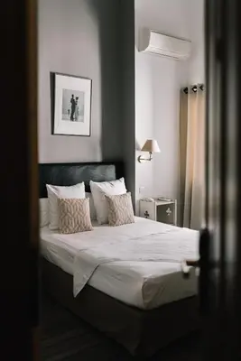 a bedroom with a bed with white sheets and pillows at Hôtel La Résidence in Narbonne