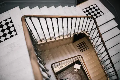 an overhead view of a spiral staircase with checkered floors at Hôtel La Résidence in Narbonne