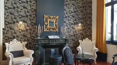a living room with two chairs and a fireplace at Hôtel La Résidence in Narbonne