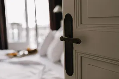 a white door with a black handle on a bed at Hôtel La Résidence in Narbonne