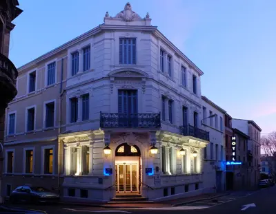 a large white building with a door on a street at Hôtel La Résidence in Narbonne