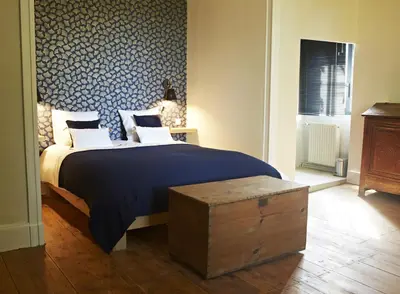 a bedroom with a large bed with a blue patterned wall at Chambres d'hôtes du Domaine de Bonnery in Caucalières
