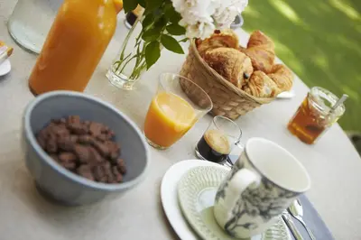 a table with a breakfast of bread and orange juice at Chambres d'hôtes du Domaine de Bonnery in Caucalières