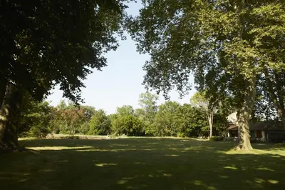 a large grass field with trees in a park at Chambres d'hôtes du Domaine de Bonnery in Caucalières
