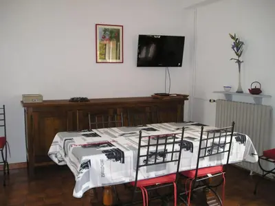 a room with a table with chairs and a tv at GITE MAMIE LAURENCE in Gruissan