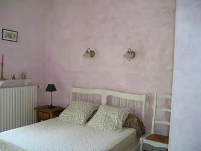 a bedroom with a white bed and pink walls at GITE MAMIE LAURENCE in Gruissan
