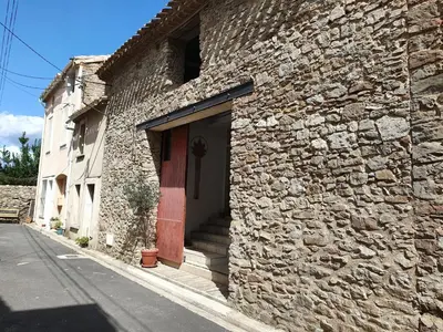 a brick building with a red door and a sidewalk at Olonzac Escape Pool & Charm in Olonzac