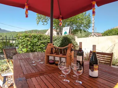 a wooden table with wine bottles and glasses on it at Au Petit Verger in Puivert