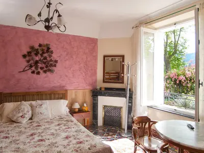a bedroom with a bed and a table and a fireplace at Au Petit Verger in Puivert