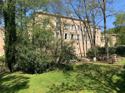 a large stone building with trees in front of it at La Manufacture Royale 1739 in Montolieu