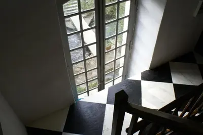 an attic room with a window and a checkered floor at La Manufacture Royale 1739 in Montolieu