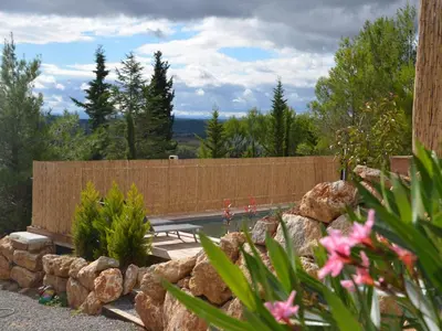 a garden with a fence and some rocks and flowers at Stylish villa in Beaufort with private pool in Beaufort