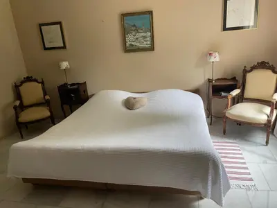 a bedroom with a white bed and two chairs at Residence le Petit Paradis in Labastide-Rouairoux