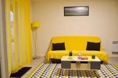 a yellow bed in a room with a table at Appart Chrystal in Carcassonne