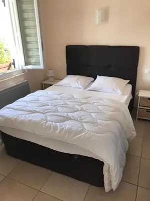 a large bed with white sheets and a black headboard at Maisonnette El Puy in Molitg les Bains