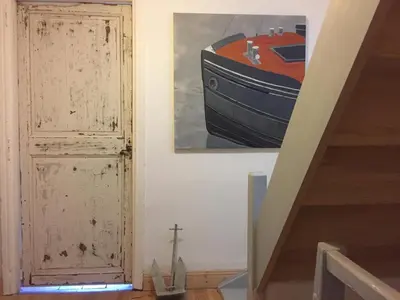 a painting of a boat on the wall next to a door at Le Petit Relais du Canal in Trèbes