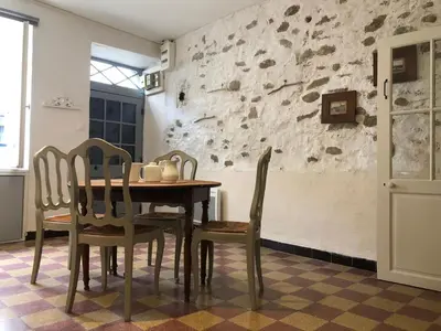 a table and chairs in a room with a stone wall at Le Petit Relais du Canal in Trèbes