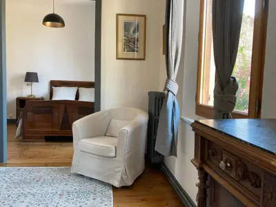 a living room with a white chair and a bed at Number15 Guesthouse Carcassonne in Carcassonne