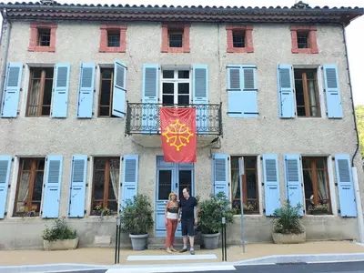 two people standing in front of a building with a flag at Burlats in Burlats