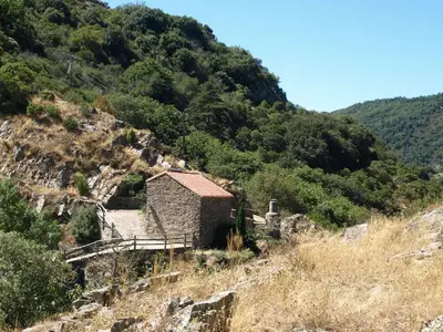 an old building on a hill with a mountain at La Bergerie et La Grange du Moulin de Trédos in Vélieux