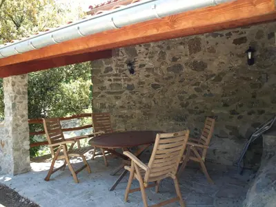 a wooden table and chairs on a patio at La Bergerie et La Grange du Moulin de Trédos in Vélieux