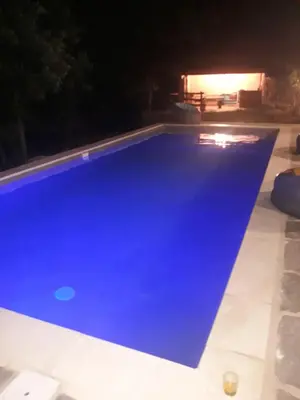 a blue swimming pool at night at La Bergerie et La Grange du Moulin de Trédos in Vélieux