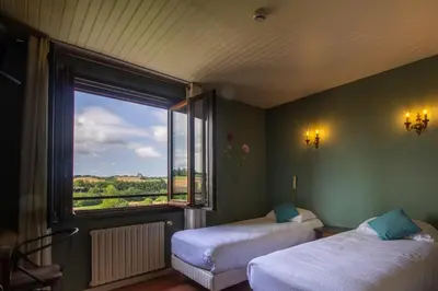 a room with two beds and a large window at Logis Hôtel et Restaurant La Bombardière in Cuq-Toulza